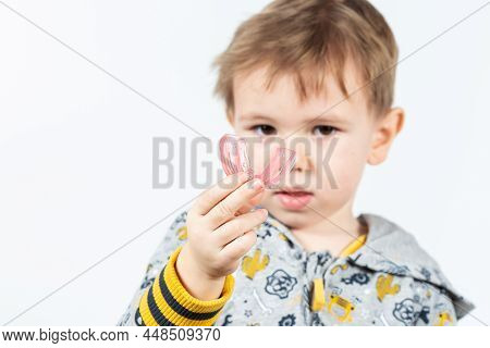 Cute Little Caucasian Boy With Blond Hair Is Holding A Pink Dental Myofunctional Trainer On White Th