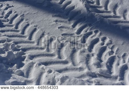 Close Up Car Tire Tracks In The White Snow. Low Sun, Blue Shadows. Top View. Winter Roads. Passabili