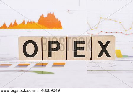 On A Light Background, Graphs, Diagrams And Wooden Cubes With The Word Opex - Operational Expenditur