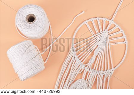 Rolls Of Cotton Macrame Cord And Finished Wall Hanging Object On Beige Background