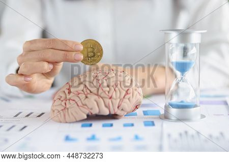 Close-up Of Businesswoman Put Bitcoin In Human Brain Model, Hourglass On Table. Create Idea, Find Wa