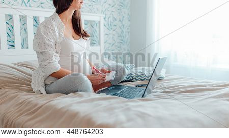 Pragnant Woman With Laptop On Bed. Pregnant Working At Home.