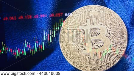 Cryptocurrency Bitcoin Gold Coin And Defocused Chart Background.