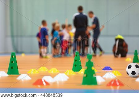 Futsal Soccer Training Court. Kids In A Group With Coaches In Blurred Background. Kids On Physical E