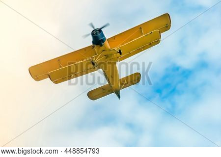 Two-pilot Yellow Airplane Boldly Making Turns In The Blue Cloudy Sky Close-up