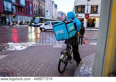 Riga, Latvia - February 9, 2022: Wolt Bicycle Courier At Work In Riga. Food Delivery Service During 