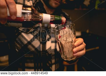 Bartender Preparing Refreshing Cocktail, Pouring Berry Syrup Into Glass With Ice