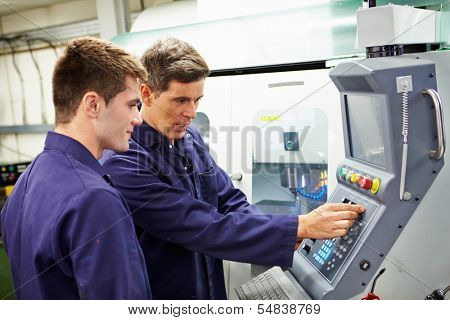 Engineer And Apprentice Using Automated Milling Machine