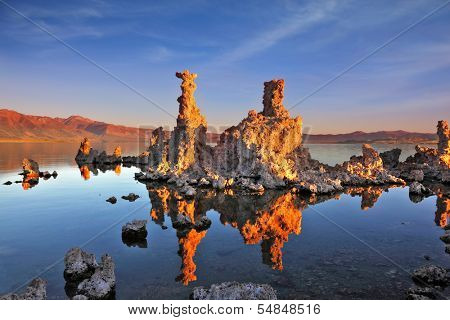 The magic of Mono Lake. Outliers - bizarre calcareous tufa formation on the smooth water of the lake. Orange sunset
