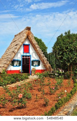 Charming white cottage with a thatched roof and gable small garden with flowers. Picturesque house-museum of the first colonists to Madeira. 