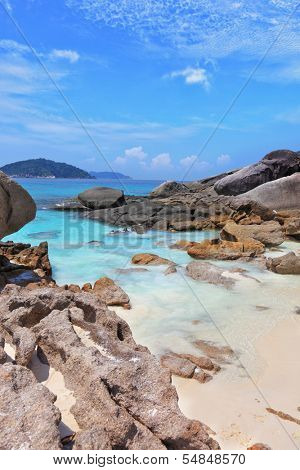 Similansky islands, Andaman Sea, Thailand. The thinnest white sand of a beach adjoins with huge brown rocks and azure water.