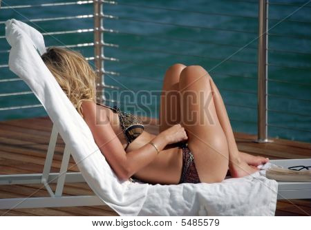Mulher jovem, banhos de sol ao pôr do sol
