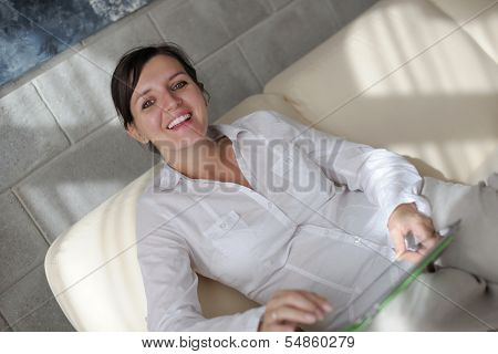 happpy young woman reading magazina at home in comfortabel sofa and bright living room