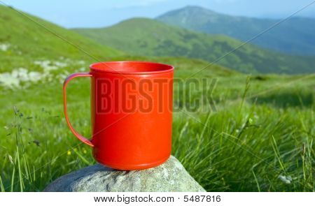 Copo vermelho em pedra no campo de montanhas