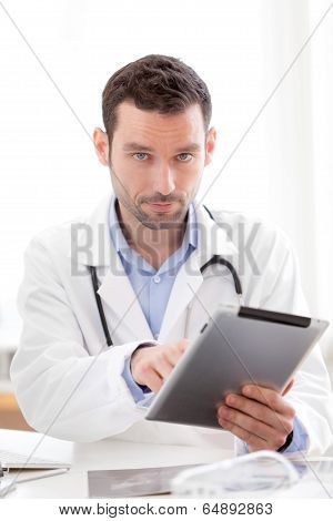 Portrait Of A Young Doctor Using Tablet At Work