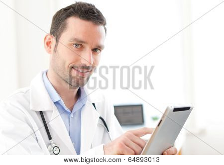 Portrait Of A Young Doctor Using Tablet At Work
