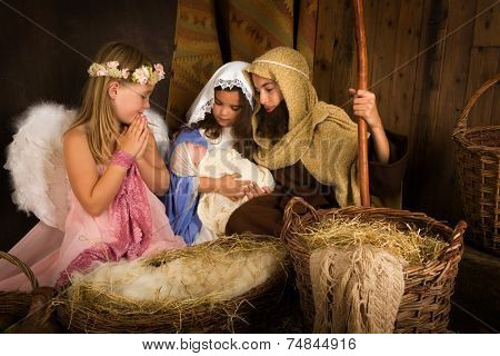 Little 7 year old angel visiting a nativity scene reenacted with a doll