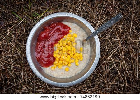 porridge with corn and tomato ketchup in tourist plate in outdoor