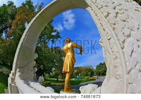 Elegant bronze statue with violin shines in the bright summer sun.  Dynamic sculptural portrait of the King of Waltz - Johann Strauss. 