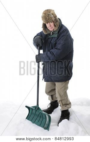 A bundled, senior adult man looking at the viewer as he stands with his shovel in the snow.  On a white background.