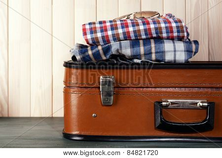 Vintage suitcase with clothes on wooden background
