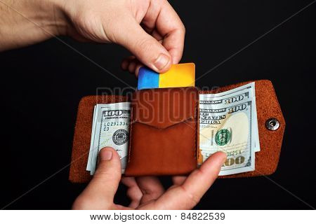 Man holding hand made leather wallet with cards and money on black background