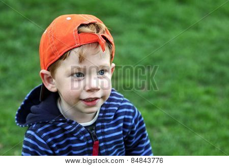 Cute boy wearing an orange baseball cap outside