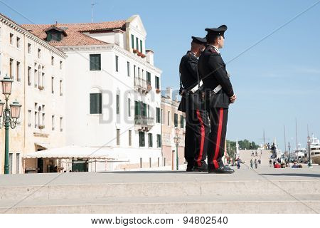 Two Carabinieri On Steps Near Venice Waterfront.