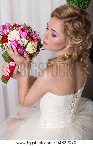 beautiful gentle young girl happy bride in a white dress sitting on a chair and smelling a bridal