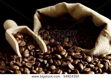 Overturned Bag Full Of Coffee Beans On Black With Spatula