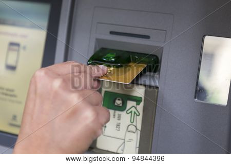 People Stand In A Queue To Use The Atms Of A Bank. Person Receiving Money From The Atm.