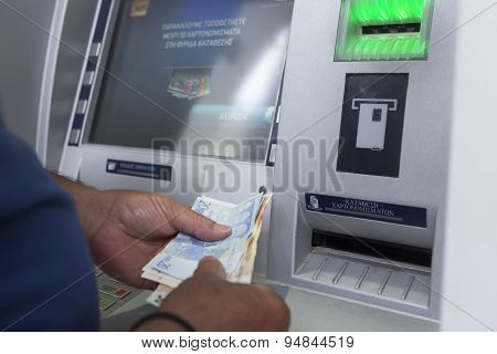 People Stand In A Queue To Use The Atms Of A Bank. Person Receiving Money From The Atm.