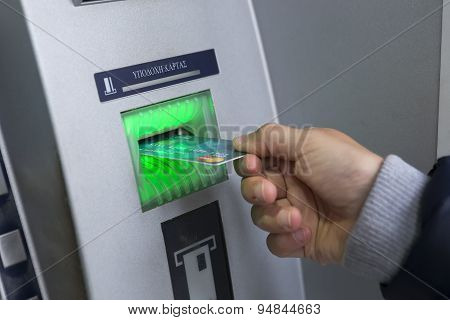 People Stand In A Queue To Use The Atms Of A Bank. Person Receiving Money From The Atm.