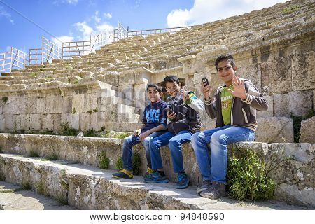 View of smiling boys sitting in the Roman Theater of Jerash, Jordan