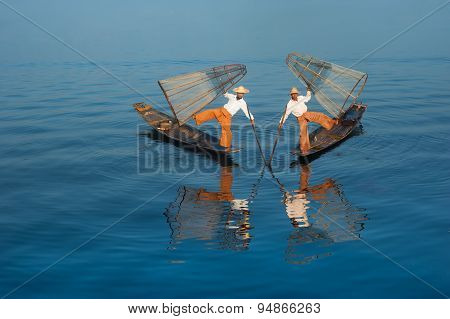 Burmese fisherman on bamboo boat catching fish in traditional way. Inle lake, Myanmar