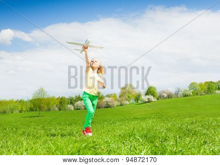 Blond girl holding airplane toy during running