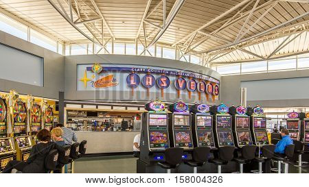 LAS VEGAS NV/USA - NOVEMBER 7 2016: People playing slot machines at McCarran International Airport terminal below a 