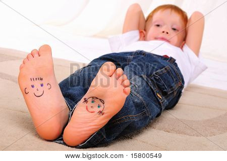 kleine Gesichter gemalt auf den Sohlen eines jungen Mannes