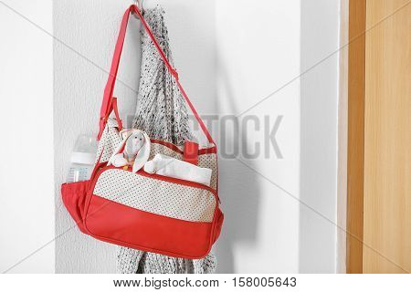 Mothers bag with toy and accessories hanging on wall hook