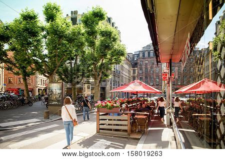 STRASBOURG FRANCE - JUL 4 2016: Woman walking near Chez Marco's Bar Cintra in central Strasbourg waiting for customers on a bright sunny day for best cocktails and alcohol or sweet beverages inside or on the best terrace