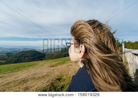 Young beautiful woman wearing glasses contemplating mountains and hills looking toward new experiences love job dream house children and bright future
