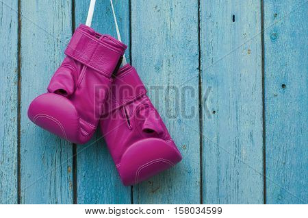 Pink boxing gloves on blue cracked wooden background empty space on the right