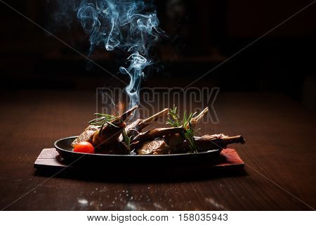 Tasty roast ribs with smoke on the pan on a wooden table