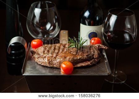 Tasty grilled steak with tomato and vine on the pan on a wooden table
