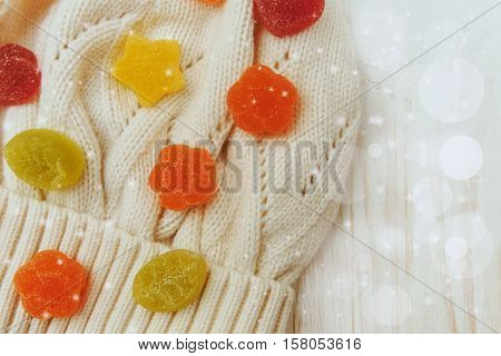 Background from jujube colorful candies in the knitted white hat.Wooden table