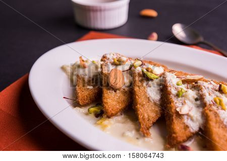 Shahi Tukda prepared - deep fried bread in ghee, garnish with sweetened cream and dry fruits.