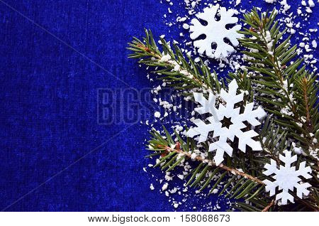 Christmas decoration.White snowflakes and snowy fir tree branch on blue background with copyspace.Christmas snowflakes.Top view.Winter holidays,Christmas or Happy New Year concept.