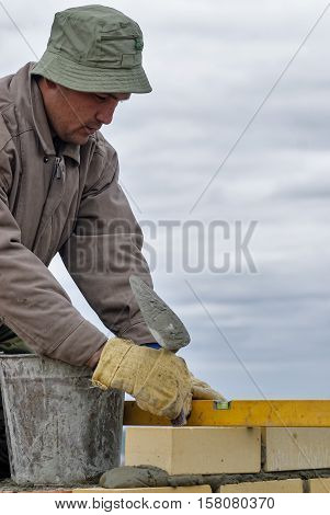 Tyumen, Russia - May 23, 2008: Construction of 18 floor brick residental house at streets intersection of Gercena and Chelyuskincev. Construction mason worker bricklayer installing brick with trowel