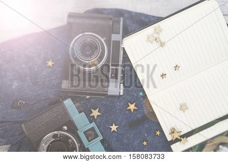 Old photo camera and notebook on the wooden background. Accessories: branches, heather and jeans cloth