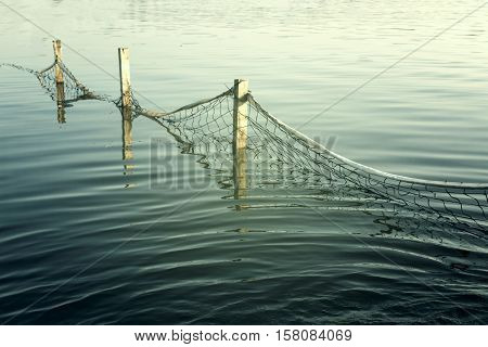 Grid on the water near to the pier. Waves on the turquoise water